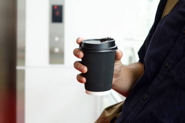 istock Hand holding disposal cup in front of elevator 1308721842