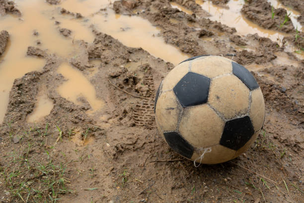 Old soccer ball on wet dirt field