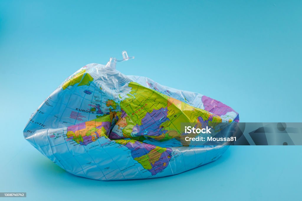 Global warming, climate catastrophe and environmental trouble concept with deflated globe isolated on blue background Deflated Stock Photo