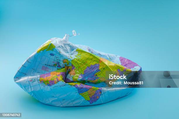 Global Warming Climate Catastrophe And Environmental Trouble Concept With Deflated Globe Isolated On Blue Background Stock Photo - Download Image Now