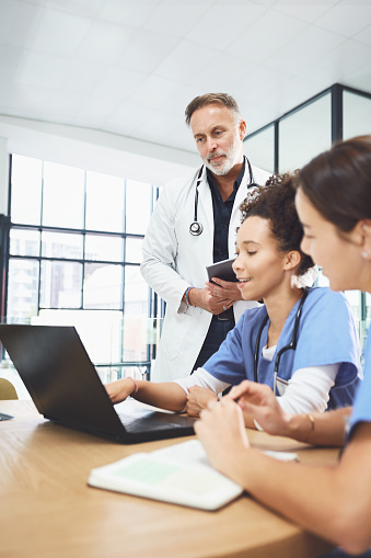 Shot of a team of doctors using a laptop during a meeting in a hospital