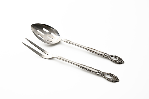 High angle view of big slotted kitchen spoon and barbeque fork, isolated on white with clipping path.