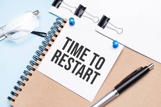 istock Notepad with Time to Restart text on the office table with glasses, notepad and paper with clips. 1308755151