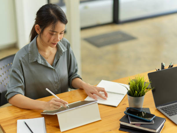 istock Businesswoman concentrating on her work with digital tablet and notebook on office desk 1308758687