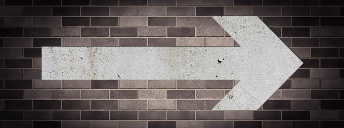 Brown brick wall and concrete arrow