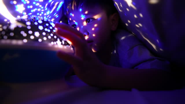 Asian boy turn on star light lamp for bedtime