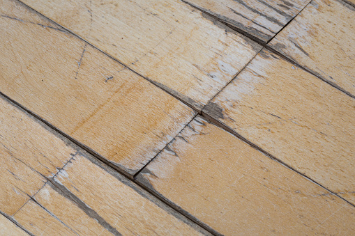 old parquet or laminate flooring deformed by water exposure. scratched floor covering close-up.