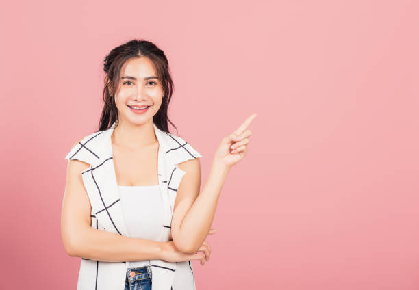 istock woman standing smiling indicate finger empty space 1308776444