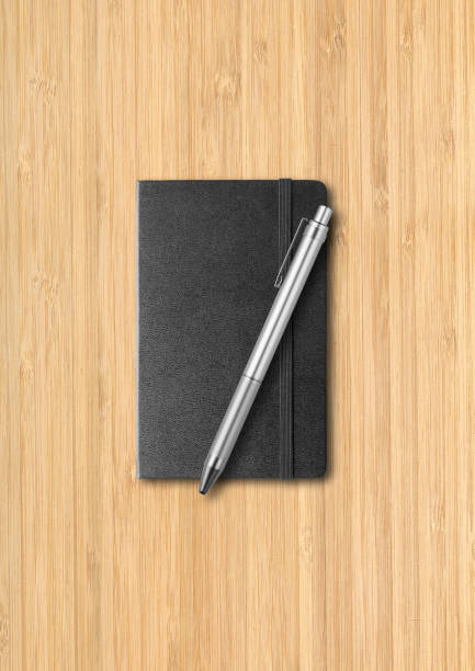 istock Black closed notebook with a pen on wooden background 1308779810