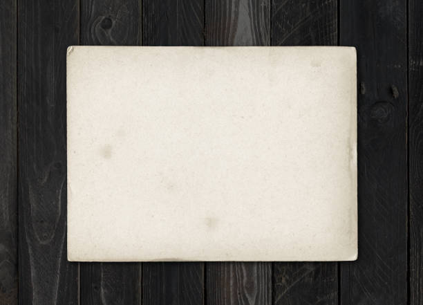 istock Old textured paper sheet on a black wood table 1308780872