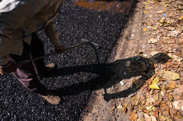 a road is being constructed. the shadow of the one who is building the road (worker/laborer) has fallen from the built road to the outside of the road.  this means make your own path, clear your way. - success failure dreams road sign imagens e fotografias de stock