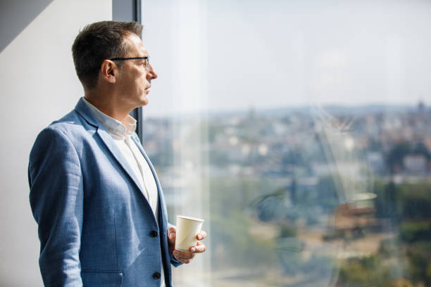 istock Businessman looking through window on coffee break 1308787424