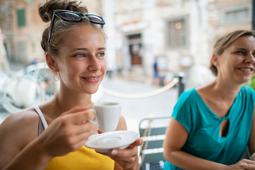 Family sightseeing beautiful Italian town. Teenage girl and her mother are enjoying a cup of espresso.\nNikon D850