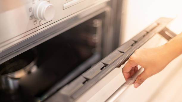 istock Female hand professional cook opening electric oven, while preparing dinner at home. Hobby, lifestyle. Selective focus. Web Banner 1308794025