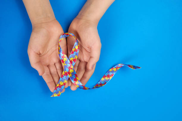 istock World Autism awareness day. Autistic boy hands holding puzzle pattern ribbon on blue background 1308798664