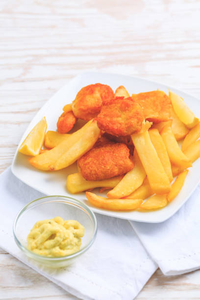 istock Fish and chips with dip and lemon on white plate 1308798679