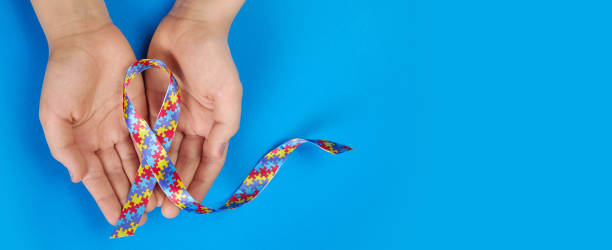 istock World Autism awareness day. Autistic boy hands holding puzzle pattern ribbon on blue background 1308798686