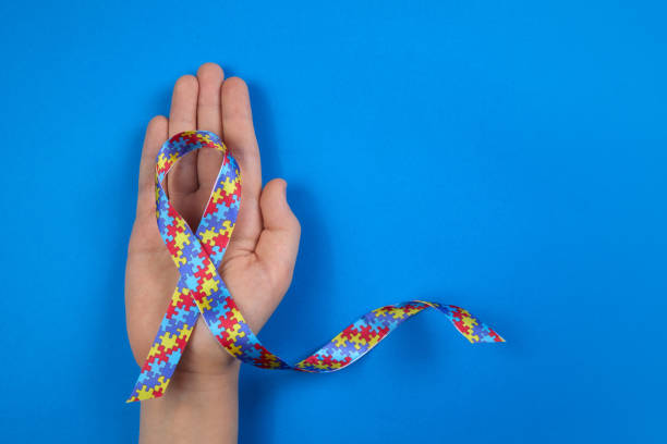 istock World Autism awareness day. Autistic boy hand holding puzzle pattern ribbon on blue background 1308798736