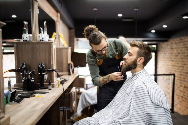 cliente durante barba rasatura in barbiere - negozio del barbiere foto e immagini stock