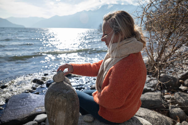istock Woman stacking rocks by the lake, relaxing moment 1308801245