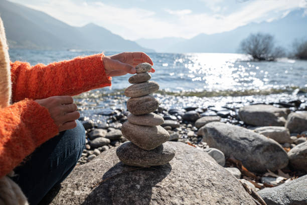 detail of person stacking rocks by the lake - stack rock imagens e fotografias de stock