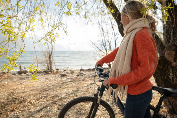 istock Woman walks by the lakeshore with her bicycle, Spring 1308802473