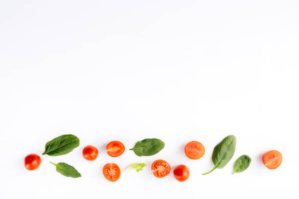 istock Red cherry tomatoes, green spinach leaves on white background. Healthy eating 1308802475