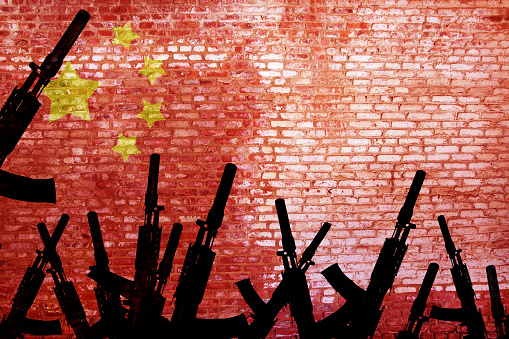 Automatic rifles are raised against the background of the Chinese flag