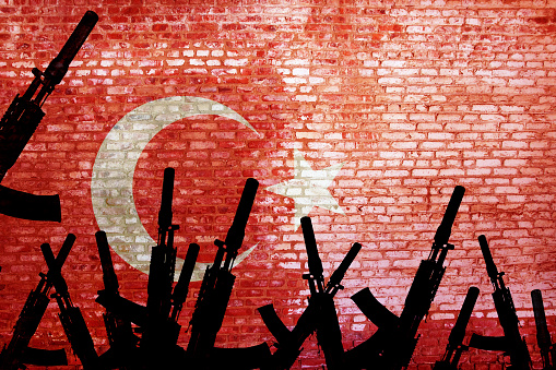 Automatic rifles are raised against the background of the Turkish flag