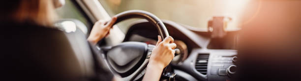 Driver driving a car on asphalt road in summer day at park. Driver driving a car on asphalt road in summer day at park. Woman at steering wheel driving steering wheel stock pictures, royalty-free photos & images