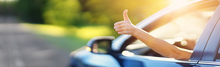 Woman inside her car gesticulate thumb up. Concept of buying car and positive emotion.