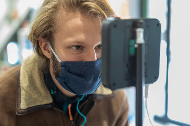 handome man in front of a thermoscanner for temperature control on the forehead, coronavirus diffusion prevention and control systems, infrared thermometer at public place entrance - infrared thermometer imagens e fotografias de stock