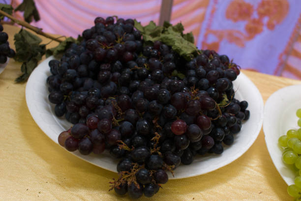 kolekcja czarnych winogron na talerzu - flocked zdjęcia i obrazy z banku zdjęć