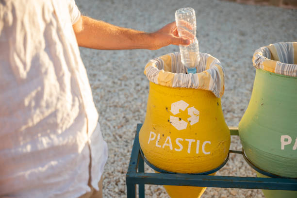 istock Person's hand throwing plastic water bottle into recycling bin 1308806880
