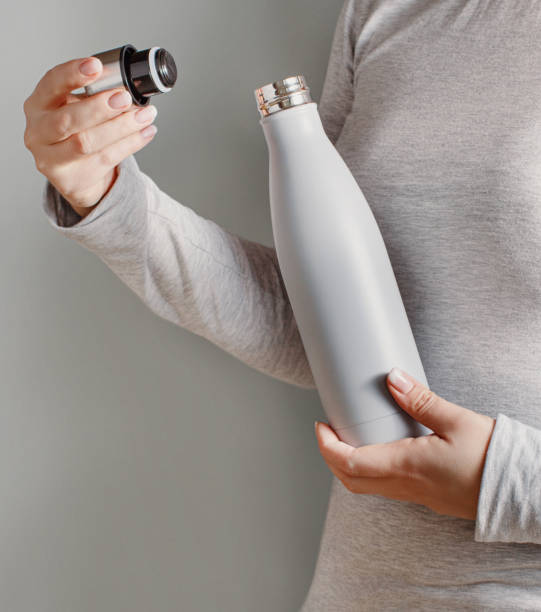istock Woman in grey tee holding grey insulated bottle on grey background 1308810244