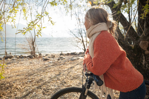 istock Woman walks by the lakeshore with her bicycle, Spring 1308810326