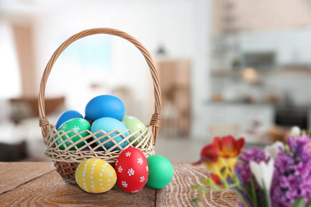 istock Wicker basket with bright painted Easter eggs on wooden table indoors 1308810671