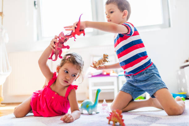 Children playing with toy dinosaurs Children playing with toy dinosaurs in their room. animal representation photos stock pictures, royalty-free photos & images