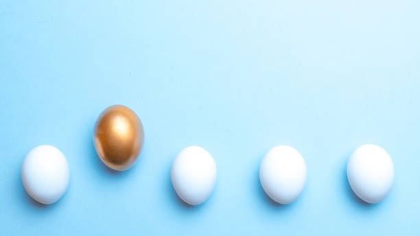 istock Easter eggs background. Golden, white colour egg on pastel blue background in Happy Easter decoration. Foil minimalist egg design, modern top view template. 1308812674