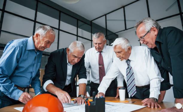 istock Aged team of elderly businessman architects works with plan in the office 1308815867