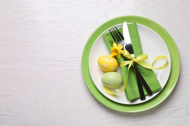 istock Festive Easter table setting with eggs on white wooden background, top view. Space for text 1308818482
