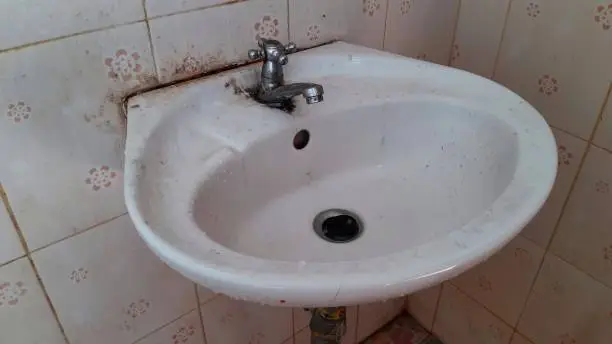 Old sink and dirty stains in bathroom.