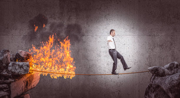 businessman walks in balance on a burning rope. businessman walks in balance on a burning rope. danger concept. tightrope stock pictures, royalty-free photos & images