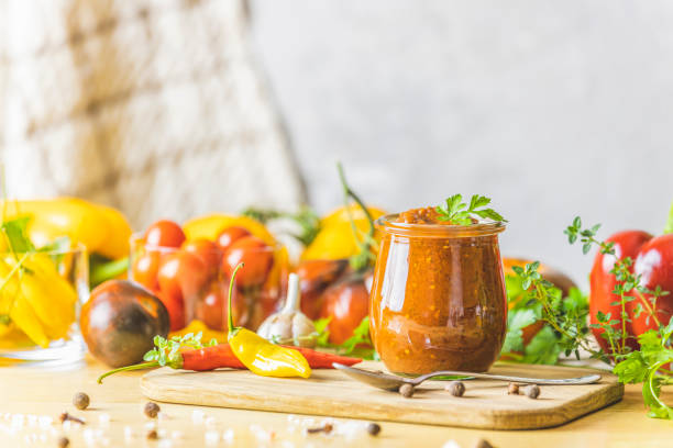 chutney de salsa de ciruela caliente enlatado natural diy casero con chile o tkemali en tarro de vidrio de pie sobre mesa de madera con ingredientes. - chutney jar tomato preserved fotografías e imágenes de stock