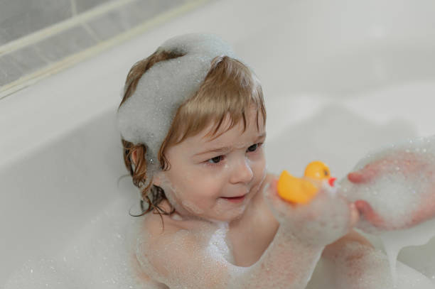 istock baby in bubble bath playing with yellow rubber duck 1308822422