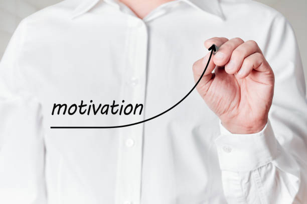 istock Businessman with pen draws a rising line graph with the word motivation on a virtual screen. Increasing motivation in business 1308823532