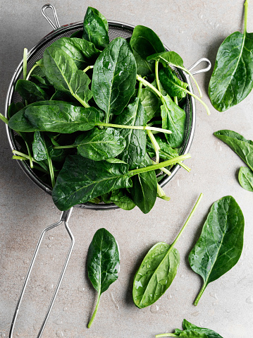 Pieces of delicious homemade quiche and fresh spinach leaves on wooden table, flat lay