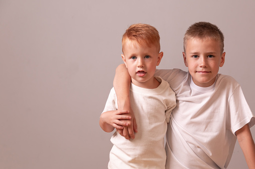 Happy Teenager and Kid Portrait. two brothers. red and blond. small and large boys. two brothers hug each other. Copy space