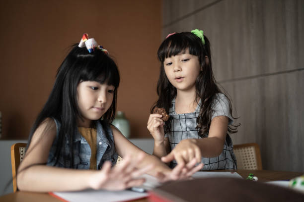 istock Sisters counting and eating cookies at home 1308829654