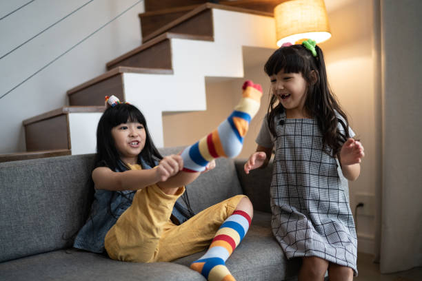 istock Happy sisters putting on colorful socks at home 1308829754